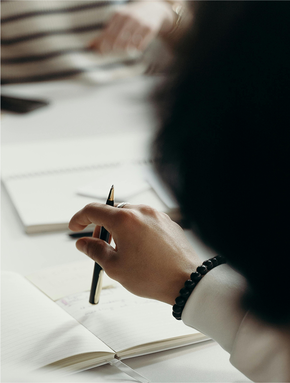 hand with pen hovering over a notepad